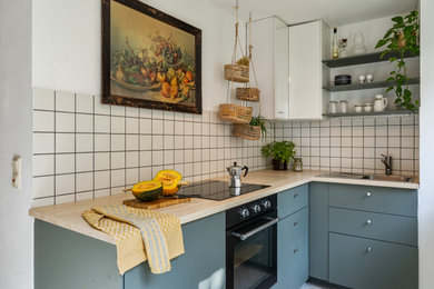Geschlossene, Kleine Stilmix Küche in L-Form mit flächenbündigen Schrankfronten, grünen Schränken, Laminat-Arbeitsplatte und Terrazzo-Boden in Stuttgart