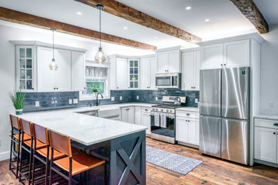 Inspiration for a mid-sized timeless u-shaped medium tone wood floor, brown floor and exposed beam open concept kitchen remodel in New York with a farmhouse sink, shaker cabinets, white cabinets, quartz countertops, multicolored backsplash, ceramic backsplash, stainless steel appliances, no island and multicolored countertops
