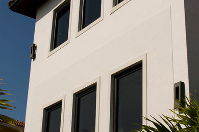 Example of a large island style white two-story concrete gable roof design in Miami