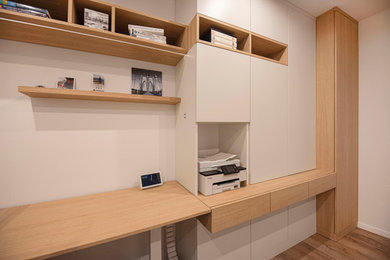 Mittelgroßes Modernes Arbeitszimmer mit weißer Wandfarbe, braunem Holzboden und braunem Boden in München