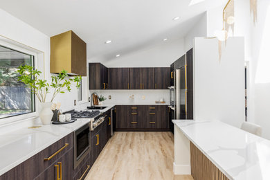 Example of a mid-sized trendy galley brown floor and vaulted ceiling eat-in kitchen design in Phoenix with a single-bowl sink, flat-panel cabinets, white backsplash, stainless steel appliances, a peninsula and white countertops