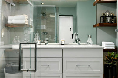 Photo of a traditional ensuite bathroom in DC Metro with white cabinets, a two-piece toilet, ceramic flooring, a submerged sink, engineered stone worktops, grey floors, a hinged door, white worktops, a wall niche and double sinks.