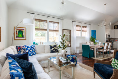 Example of a mid-sized transitional open concept dark wood floor and brown floor living room design in New Orleans with white walls, no fireplace and a media wall