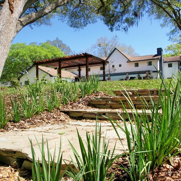 Backyard Tudor revival landscape along a natural area with a stream