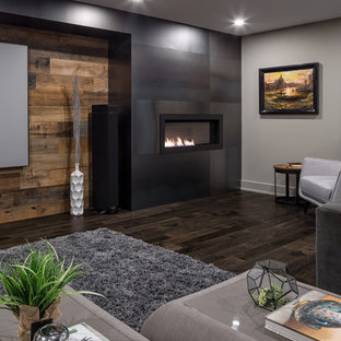 Imagen de sótano contemporáneo con suelo de madera oscura, marco de chimenea de metal y suelo marrón