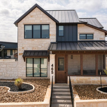 Striking modern ranch exterior with limestone façade, black metal roof, and a we