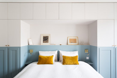 Imagen de dormitorio principal moderno de tamaño medio con paredes azules y suelo de madera clara