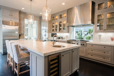 Example of a mid-sized classic dark wood floor eat-in kitchen design in Orange County with a farmhouse sink, beaded inset cabinets, granite countertops, white backsplash and an island