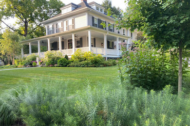 Large farmhouse beige house exterior photo in DC Metro with a clipped gable roof, a shingle roof and a gray roof