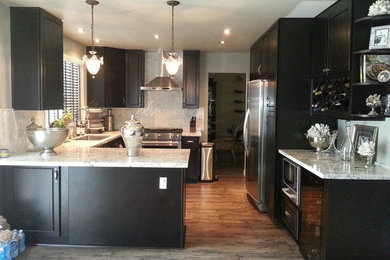 Open concept kitchen - mid-sized eclectic u-shaped porcelain tile and brown floor open concept kitchen idea in Orange County with an undermount sink, raised-panel cabinets, black cabinets, granite countertops, white backsplash, marble backsplash, stainless steel appliances and a peninsula
