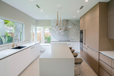 Eat-in kitchen - large modern u-shaped porcelain tile and beige floor eat-in kitchen idea in Miami with an undermount sink, flat-panel cabinets, light wood cabinets, quartz countertops, white backsplash, marble backsplash, paneled appliances, an island and white countertops