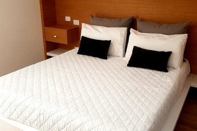 カターニア／パルレモにある中くらいなモダンスタイルのおしゃれな主寝室 (白い壁、淡色無垢フローリング、茶色い床) のレイアウト