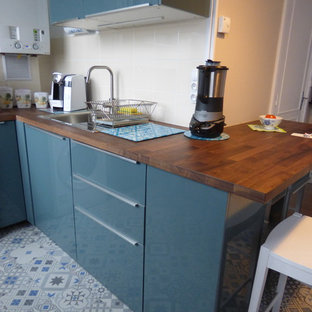 Удачное сочетание для дизайна помещения: маленькая угловая кухня в современном стиле с обеденным столом, одинарной раковиной, фасадами с декоративным кантом, синими фасадами, столешницей из дерева, бежевым фартуком, фартуком из керамической плитки, техникой из нержавеющей стали, полом из цементной плитки, синим полом и коричневой столешницей без острова - самое интересное для вас