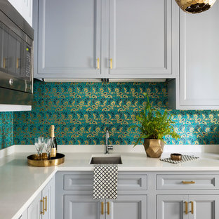 Cette image montre une grande arrière-cuisine design en L avec un évier 1 bac, un placard avec porte à panneau encastré, des portes de placard violettes, un plan de travail en stéatite, une crédence blanche, un électroménager de couleur, un sol en bois brun, un îlot central et un sol marron.