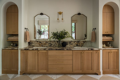 Example of a tuscan porcelain tile and double-sink bathroom design in Orange County with recessed-panel cabinets, medium tone wood cabinets and marble countertops