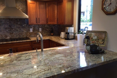 Small trendy u-shaped porcelain tile and brown floor kitchen pantry photo in Hawaii with an undermount sink, shaker cabinets, medium tone wood cabinets, granite countertops, multicolored backsplash, stone slab backsplash, stainless steel appliances and no island