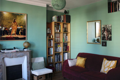 Exemple d'un salon éclectique de taille moyenne et ouvert avec une bibliothèque ou un coin lecture, un mur vert, un sol en bois brun, une cheminée standard, un manteau de cheminée en pierre, un téléviseur indépendant et un sol marron.