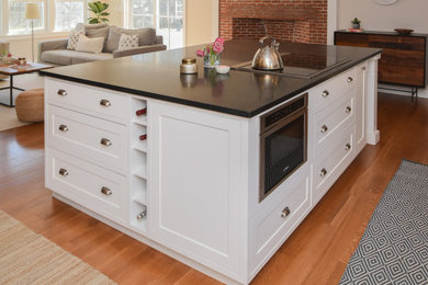 Kitchen pantry - large country medium tone wood floor and brown floor kitchen pantry idea in Other with an undermount sink, shaker cabinets, white cabinets, soapstone countertops, white backsplash, subway tile backsplash, stainless steel appliances, an island and black countertops