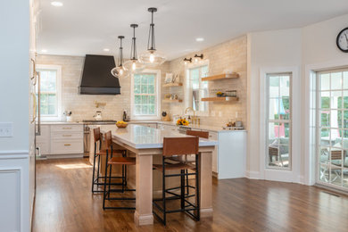 This is an example of an expansive rural galley kitchen in Other with a submerged sink, recessed-panel cabinets, light wood cabinets, engineered stone countertops, beige splashback, stainless steel appliances, dark hardwood flooring, an island, brown floors, white worktops and exposed beams.