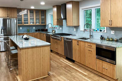 This is an example of a large transitional u-shaped kitchen in DC Metro with with island, an undermount sink, granite benchtops, glass tile splashback, stainless steel appliances, light hardwood floors, beige floor, grey benchtop, flat-panel cabinets and beige cabinets.