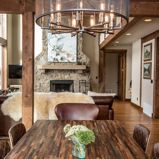 Photo of a mid-sized arts and crafts open plan dining in Other with beige walls, medium hardwood floors, a standard fireplace, a stone fireplace surround and brown floor.