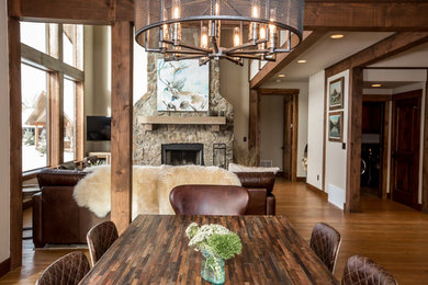 Example of a mid-sized arts and crafts medium tone wood floor and brown floor great room design in Other with beige walls, a standard fireplace and a stone fireplace