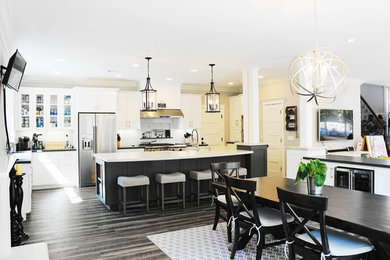 Mid-sized transitional single-wall eat-in kitchen in San Diego with a farmhouse sink, recessed-panel cabinets, white cabinets, grey splashback, stainless steel appliances, dark hardwood floors, with island, brown floor and white benchtop.