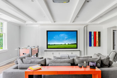 This is an example of a large modern open concept home theatre in Boston with grey walls, medium hardwood floors, a projector screen and brown floor.