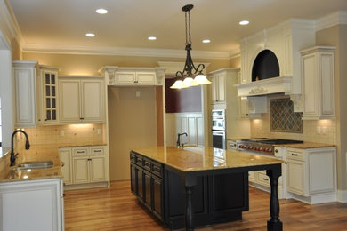 Large elegant u-shaped medium tone wood floor eat-in kitchen photo in Detroit with stainless steel appliances, an island, a double-bowl sink, raised-panel cabinets, white cabinets, granite countertops, beige backsplash and stone tile backsplash