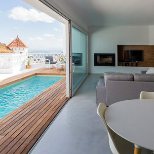 Ejemplo de salón para visitas abierto, mediterráneo, de tamaño medio, con paredes blancas, suelo de cemento, estufa de leña y pared multimedia