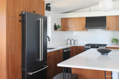 Eat-in kitchen - large modern l-shaped vaulted ceiling eat-in kitchen idea in Denver with a drop-in sink, flat-panel cabinets, medium tone wood cabinets, solid surface countertops, white backsplash, black appliances, an island and white countertops