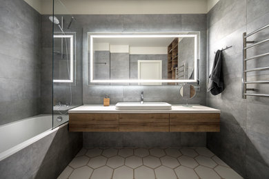 Photo of a mid-sized contemporary 3/4 bathroom in San Francisco with flat-panel cabinets, medium wood cabinets, an alcove tub, a shower/bathtub combo, gray tile, white walls, a vessel sink, white floor, an open shower and white benchtops.