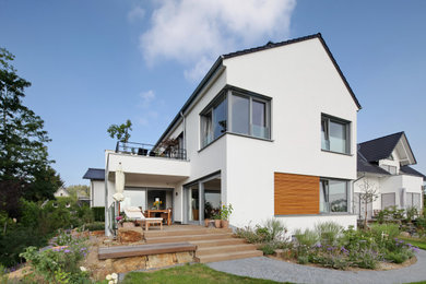 Large contemporary two-storey stucco white house exterior in Bonn with a gable roof and a tile roof.