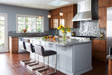 Example of a large trendy u-shaped medium tone wood floor open concept kitchen design in San Francisco with flat-panel cabinets, quartz countertops, blue backsplash, mosaic tile backsplash, stainless steel appliances and an island