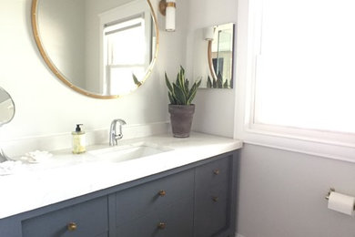 This is an example of a mid-sized transitional bathroom in Chicago with flat-panel cabinets, blue cabinets, a corner shower, a two-piece toilet, grey walls, ceramic floors, an undermount sink, engineered quartz benchtops, grey floor and a hinged shower door.