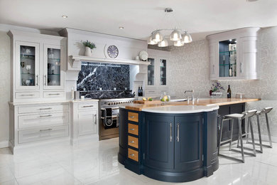 Inspiration for a medium sized traditional single-wall kitchen/diner in Belfast with a submerged sink, shaker cabinets, grey cabinets, quartz worktops, black splashback, marble splashback, stainless steel appliances, porcelain flooring, an island and grey floors.