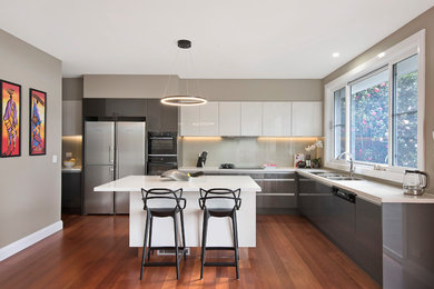 This is an example of a large modern l-shaped eat-in kitchen in Sydney with a drop-in sink, flat-panel cabinets, grey cabinets, marble benchtops, grey splashback, dark hardwood floors, with island, brown floor and white benchtop.
