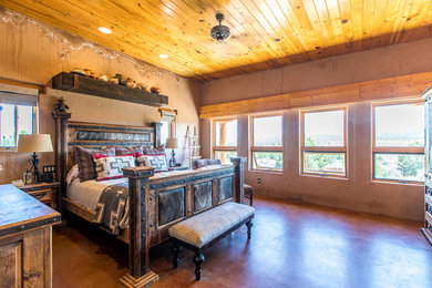 Example of a mid-sized southwest master concrete floor and red floor bedroom design in Salt Lake City with orange walls