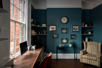 This is an example of a medium sized modern study in West Midlands with green walls, dark hardwood flooring, no fireplace, a built-in desk, brown floors and a vaulted ceiling.