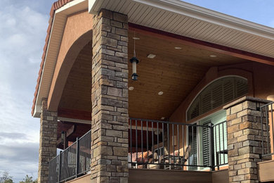 Example of a huge trendy backyard second story metal railing deck design in Other with a roof extension