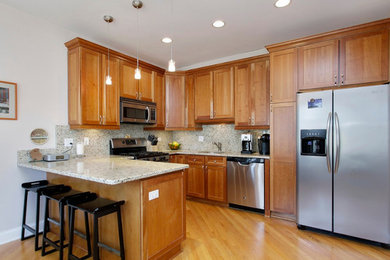 Inspiration for a mid-sized timeless l-shaped medium tone wood floor open concept kitchen remodel in Chicago with shaker cabinets, medium tone wood cabinets, granite countertops, stainless steel appliances, an island, an undermount sink, multicolored backsplash and stone slab backsplash