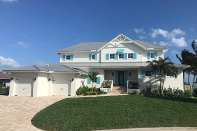 Mid-sized beach style two-storey stucco white house exterior in Miami with a hip roof and a metal roof.