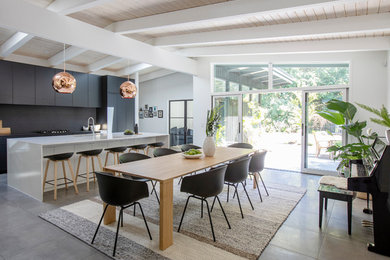 This is an example of a large midcentury kitchen/dining combo in Vancouver with white walls, no fireplace, grey floor and concrete floors.