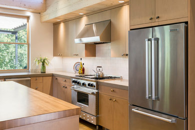 This is an example of an expansive contemporary l-shaped eat-in kitchen in Denver with an undermount sink, flat-panel cabinets, light wood cabinets, quartz benchtops, white splashback, subway tile splashback, stainless steel appliances and with island.