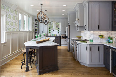 Inspiration for a large transitional l-shaped eat-in kitchen in Milwaukee with a farmhouse sink, flat-panel cabinets, grey cabinets, quartz benchtops, white splashback, subway tile splashback, stainless steel appliances, medium hardwood floors, with island and brown floor.