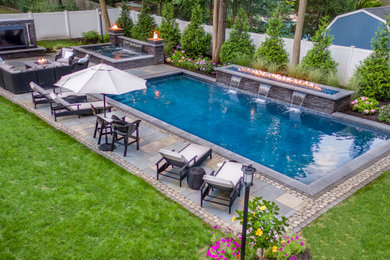 Large modern backyard rectangular pool in New York with brick pavers.