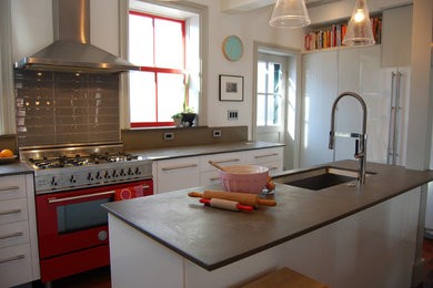 Open concept kitchen - mid-sized contemporary u-shaped medium tone wood floor open concept kitchen idea in Boston with an undermount sink, flat-panel cabinets, white cabinets, soapstone countertops, gray backsplash, porcelain backsplash, colored appliances and an island