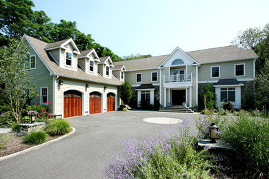 Large elegant green two-story stone exterior home photo in New York