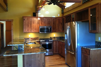 Small mountain style u-shaped medium tone wood floor eat-in kitchen photo in Denver with a double-bowl sink, shaker cabinets, dark wood cabinets, granite countertops, multicolored backsplash, stainless steel appliances and no island