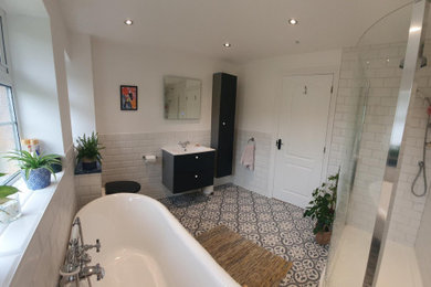 Medium sized traditional bathroom in Surrey with flat-panel cabinets, black cabinets, a claw-foot bath, a walk-in shower, a one-piece toilet, white tiles, ceramic flooring, multi-coloured floors, a hinged door, a single sink and a floating vanity unit.